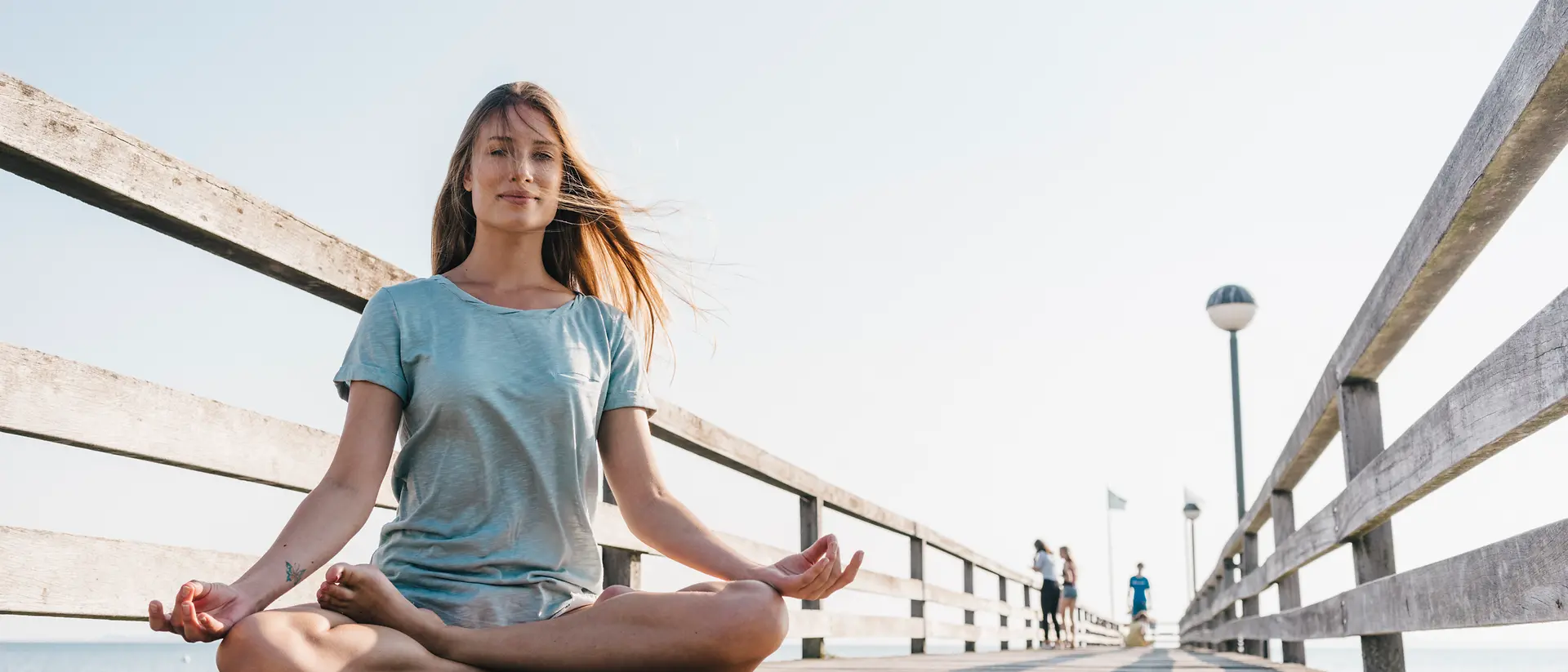 Mujer haciendo yoga sobre un muelle portuario