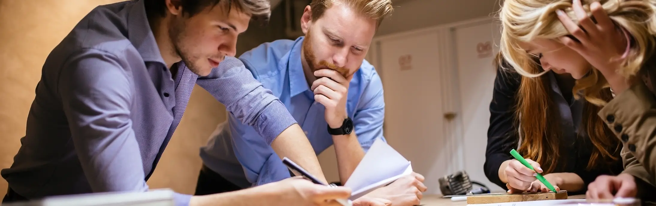 Un grupo de 4 compañeros estudiando en una mesa consultando algunos papeles