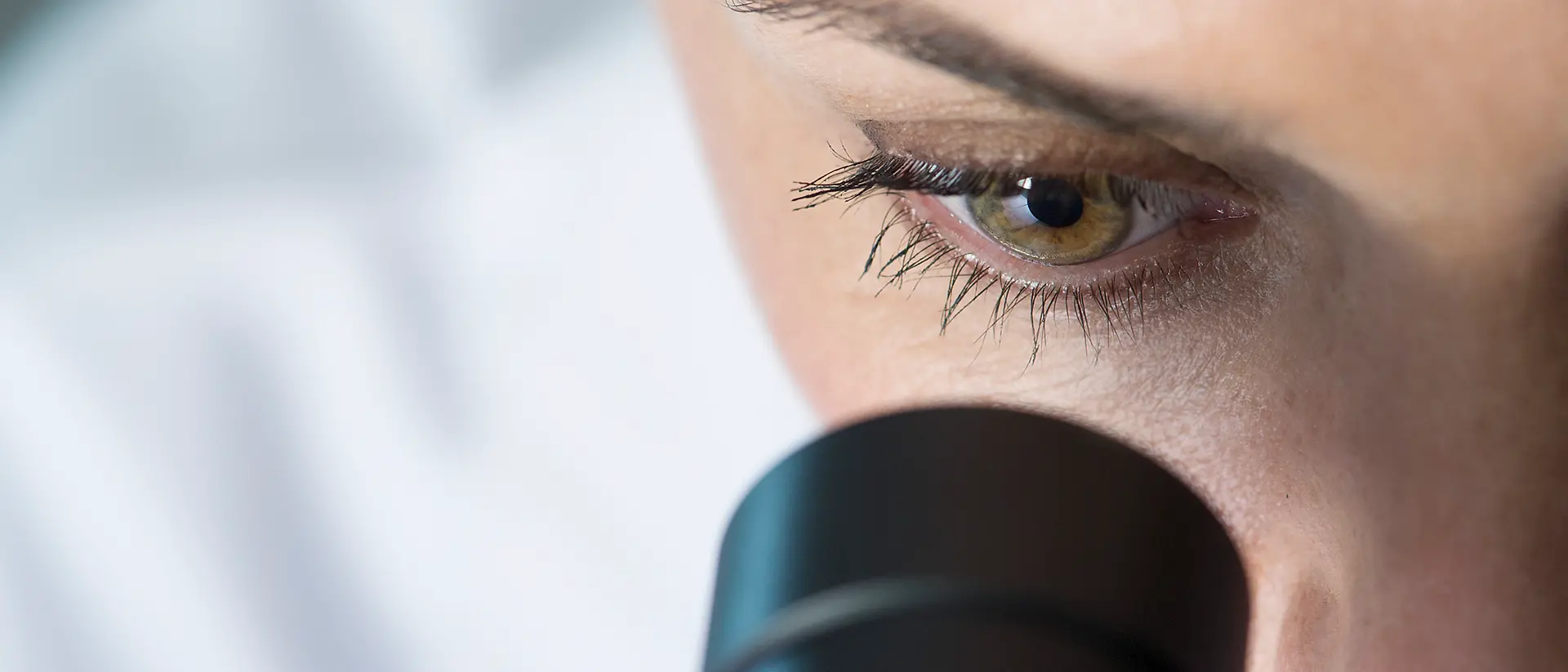 Primer plano de una mujer mirando a través de un microscopio.